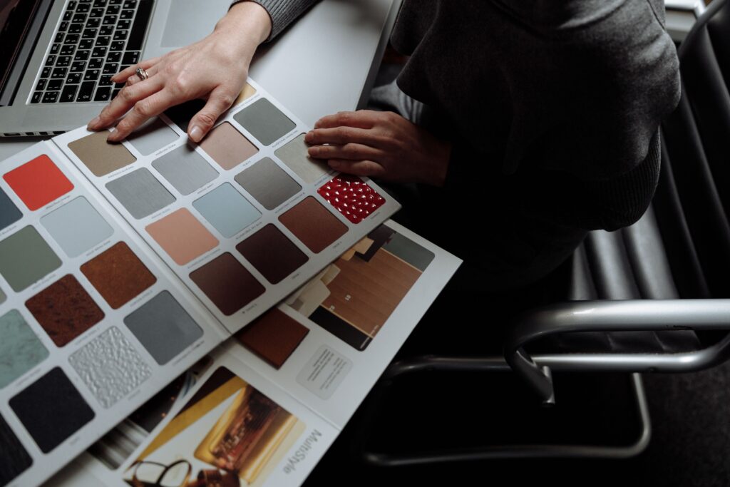 Interior designer on laptop reviewing color swatches for design project. Overhead view, modern workspace.